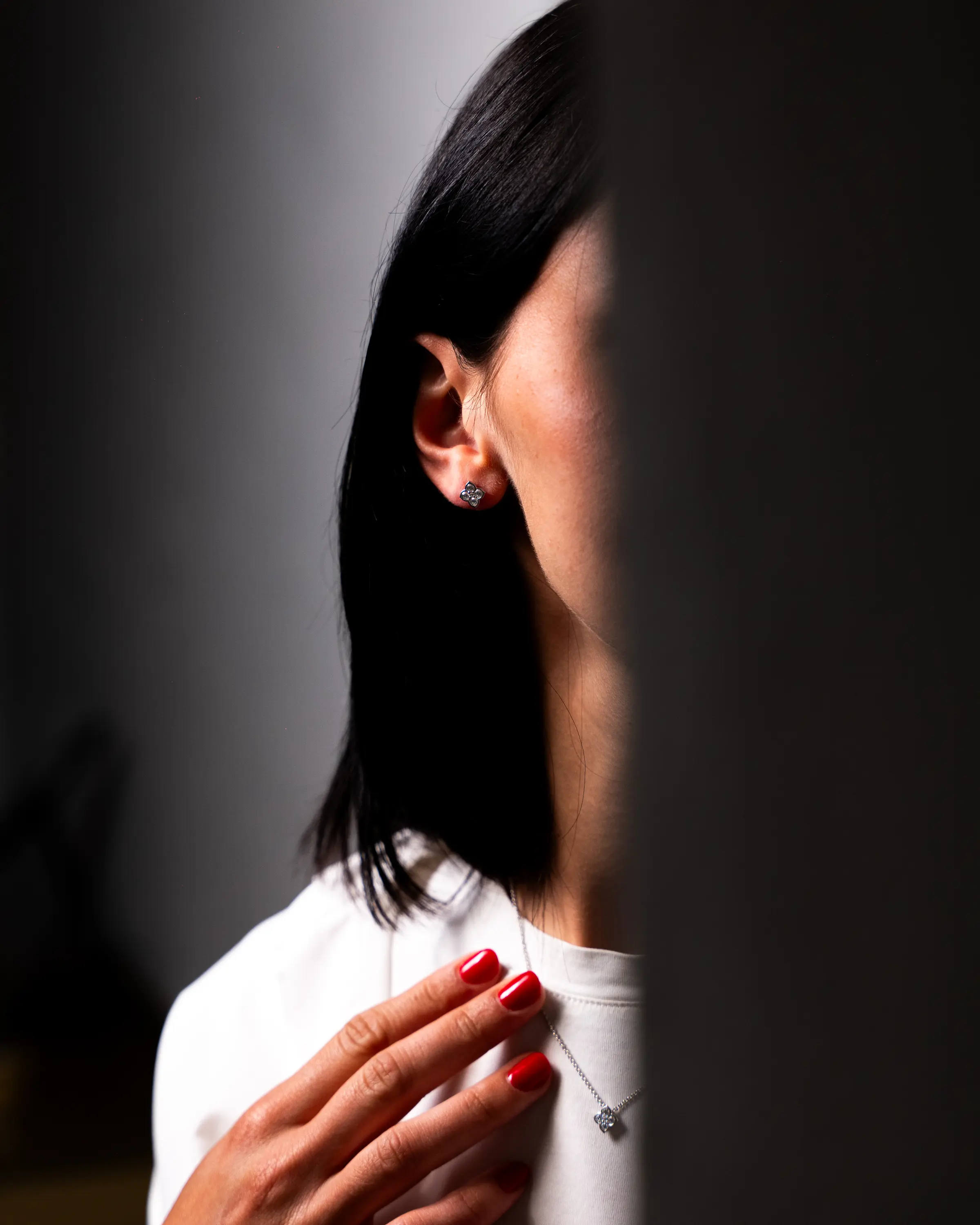 Donna di profilo con orecchino, capelli scuri e camicia bianca