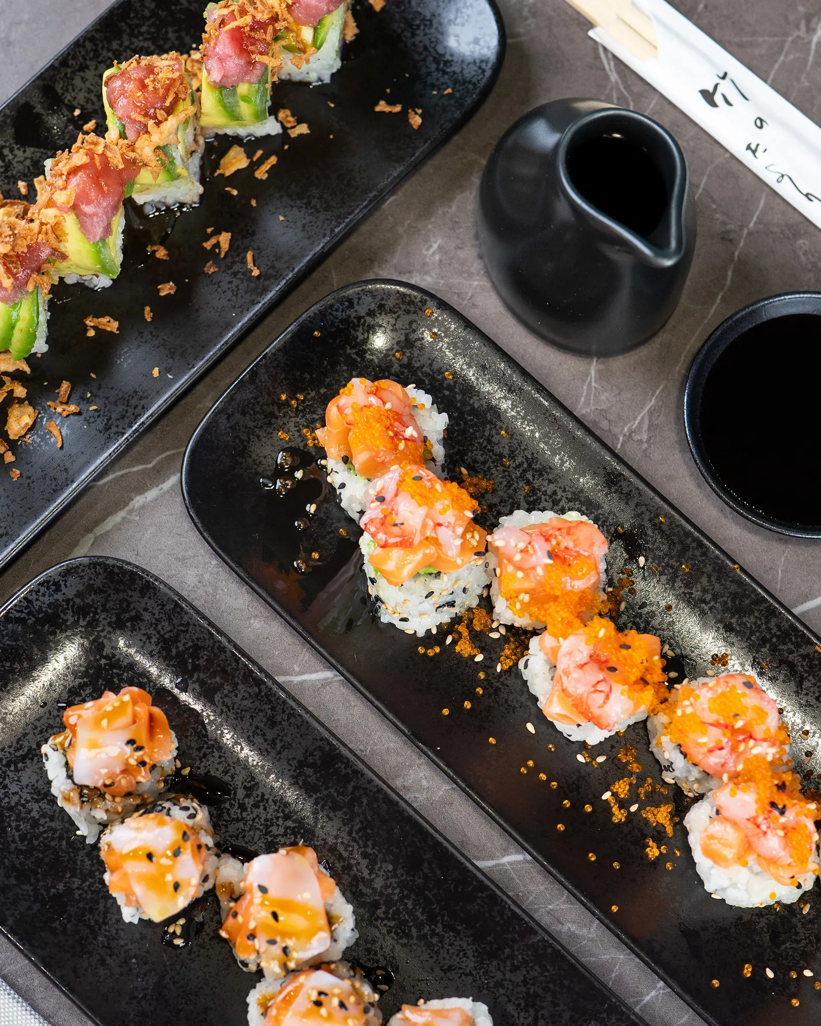 Due vassoi neri di sushi con la ciotola della salsa di soia