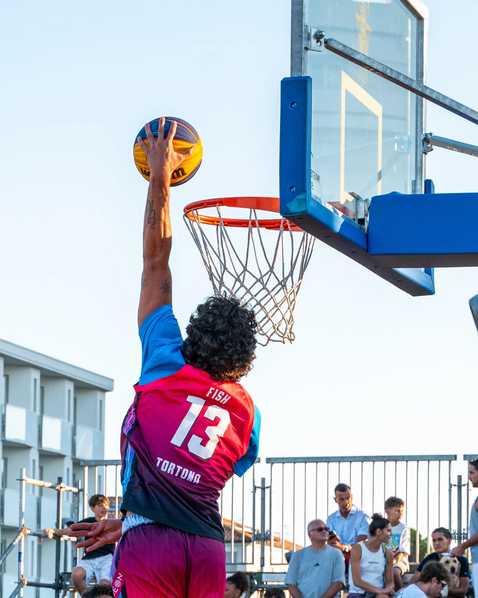 Giocatore in maglia numero 13 che va a canestro contro il cielo