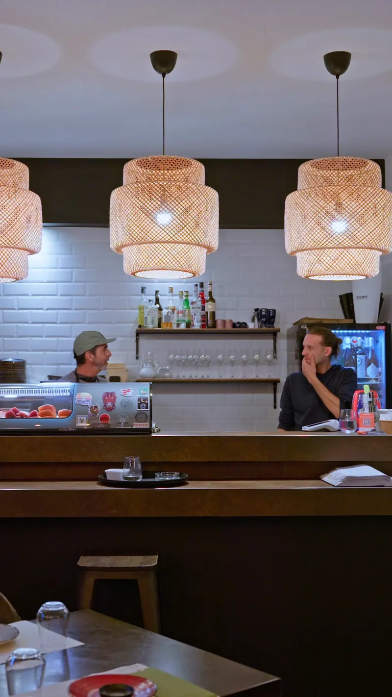 Il bancone del sushi sotto le lampade di bambú, con due persone