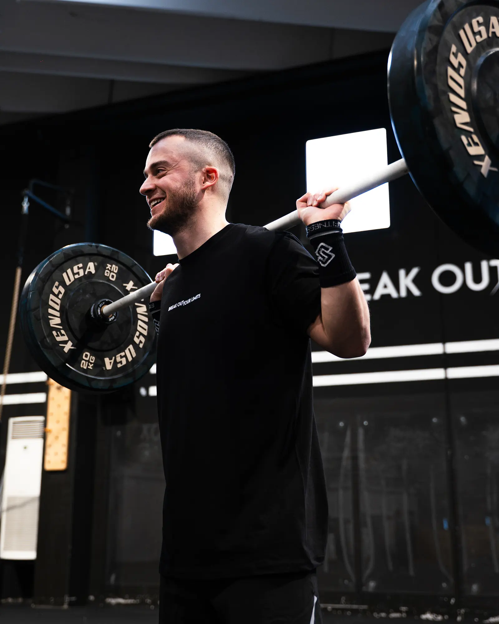 Atleta con bilanciere sulle spalle, sorride di profilo