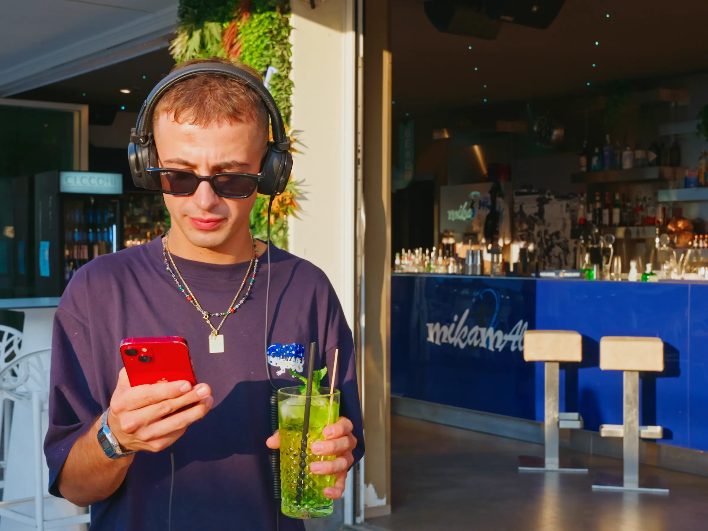 Ragazzo con cuffie e occhiali da sole con un drink davanti al bancone
