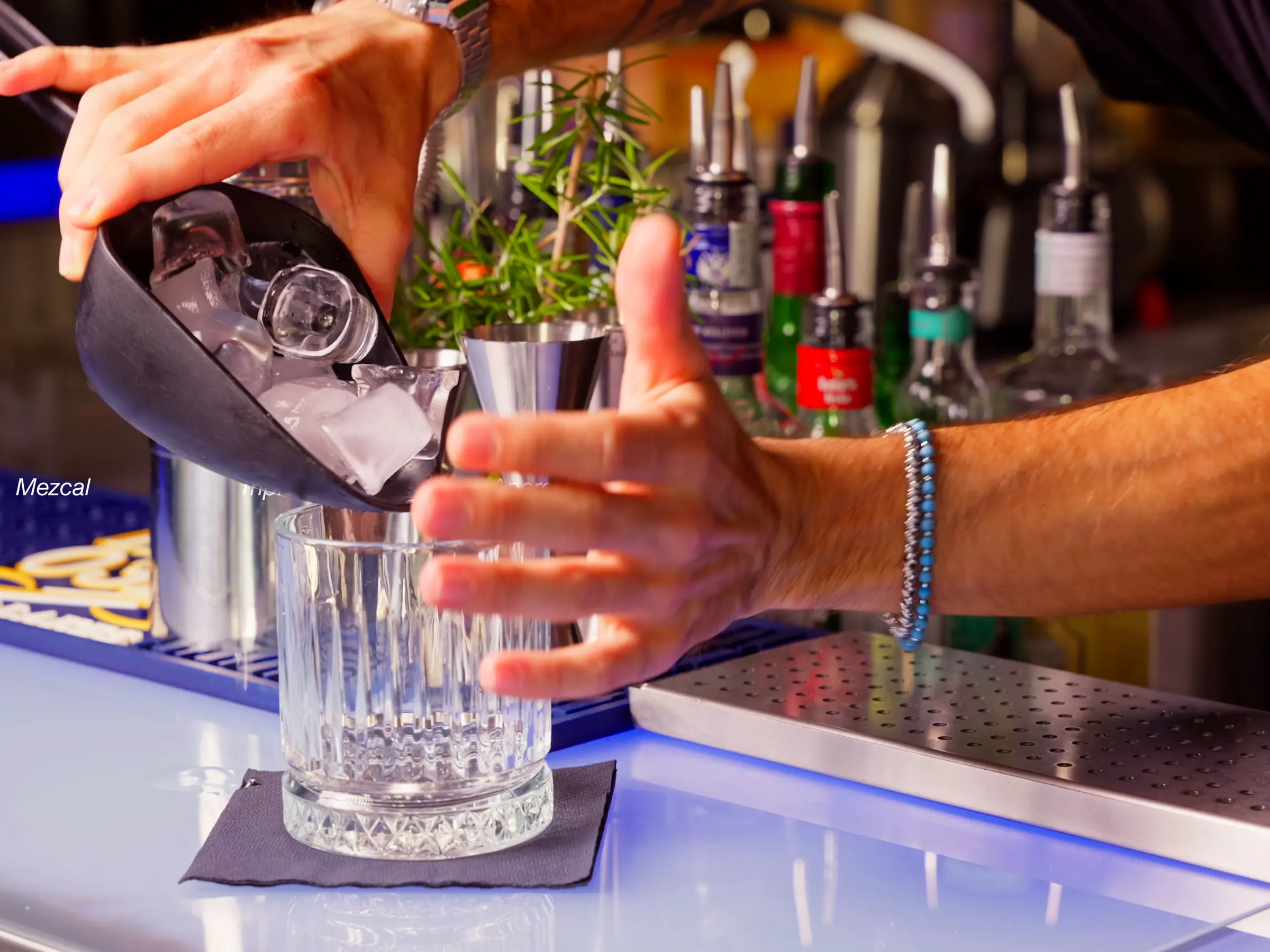 Il barman versa il ghiaccio nel bicchiere, davanti alle bottiglie