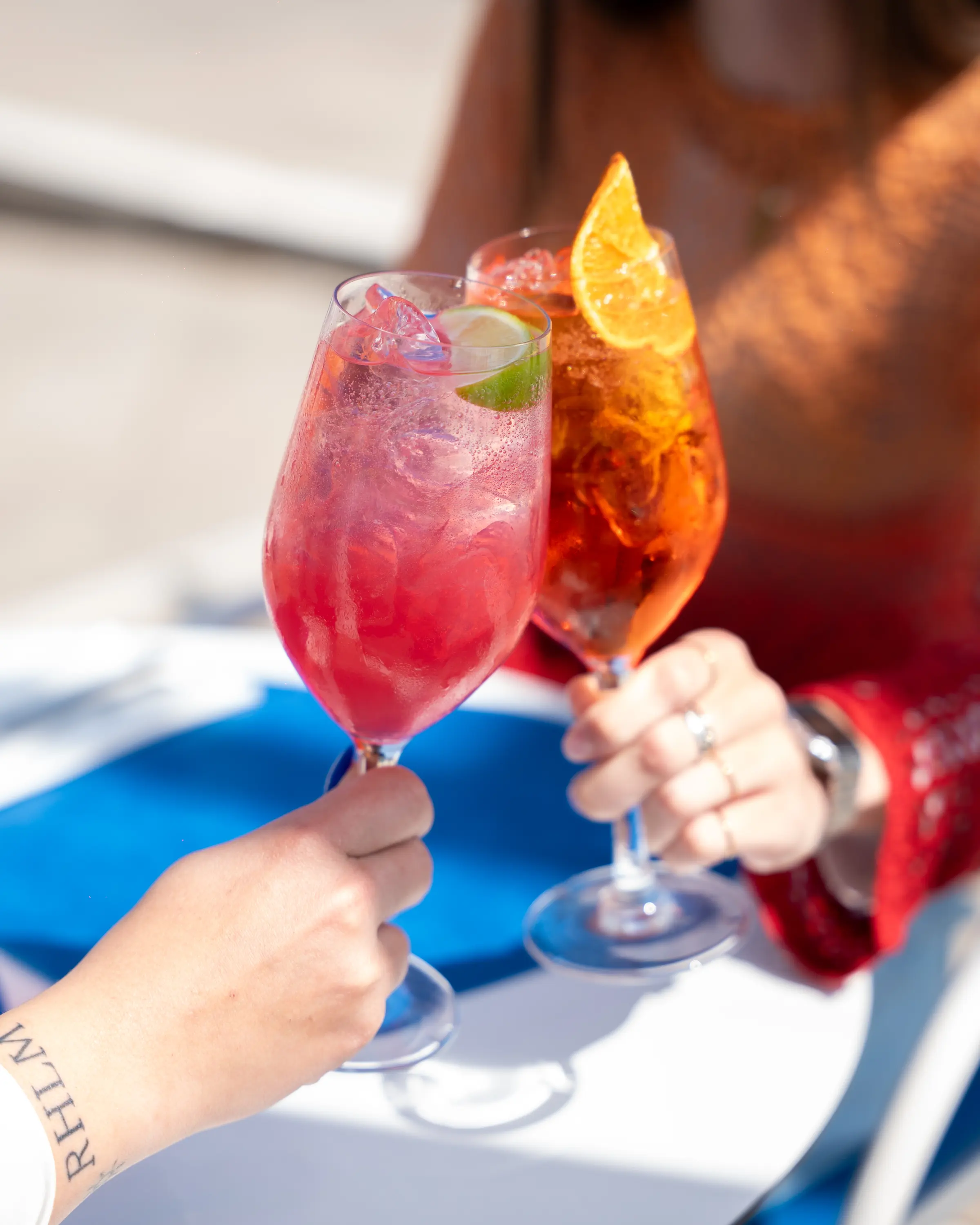 Due calici di cocktail sollevati sopra un tavolo blu
