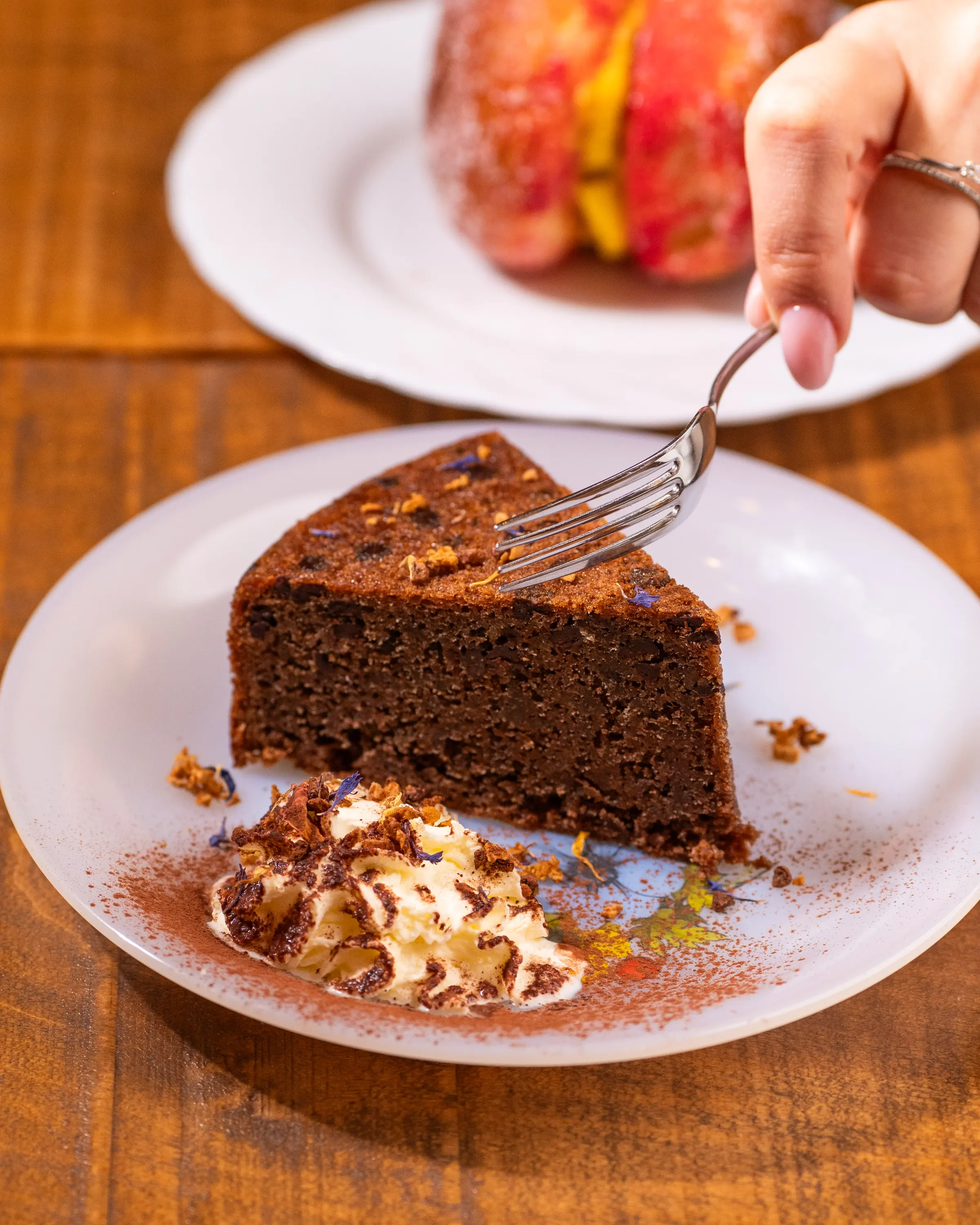Fetta di torta al cioccolato con noci, una forchetta la solleva dal piatto