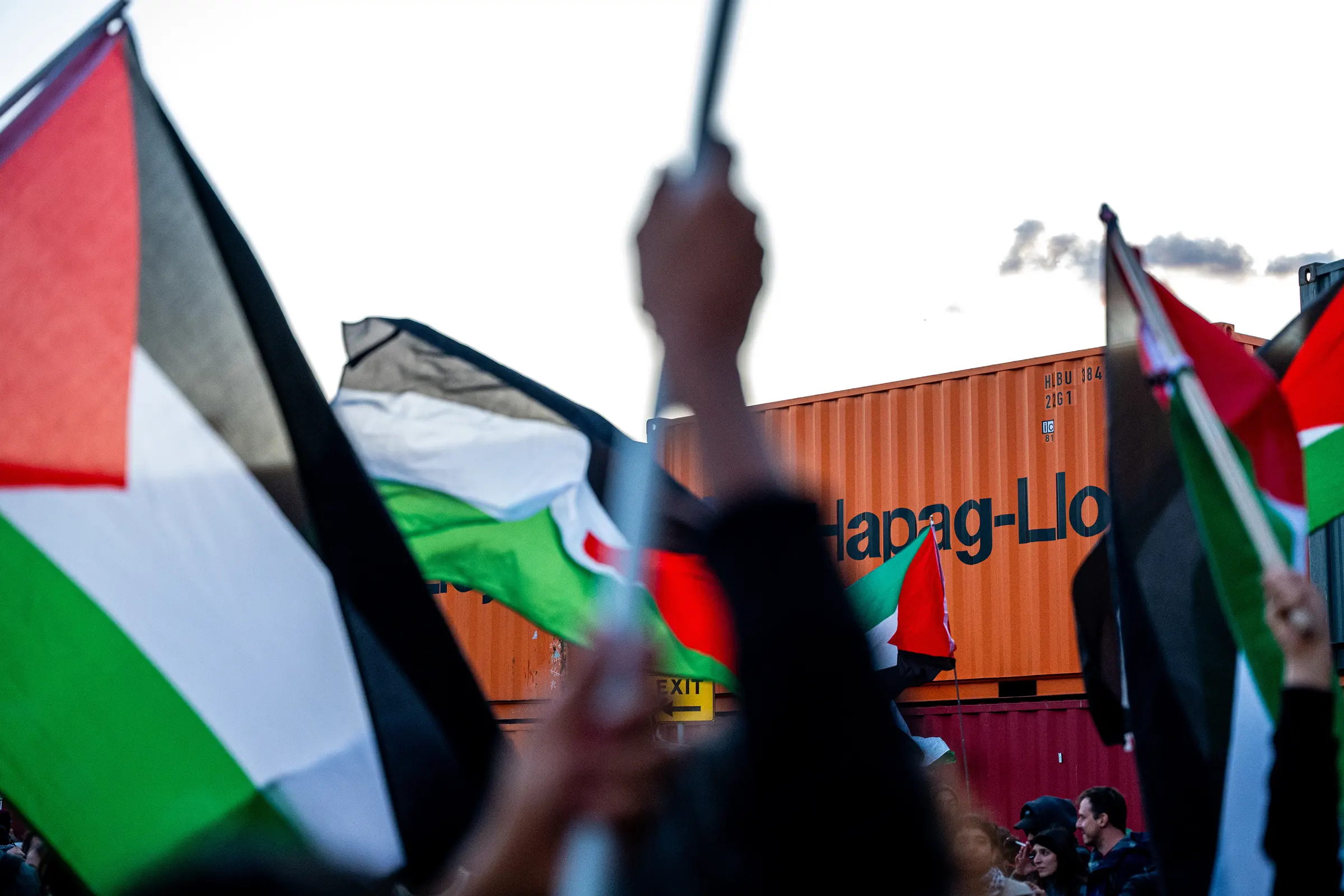 Bandiera palestinese alzata davanti a un container arancione