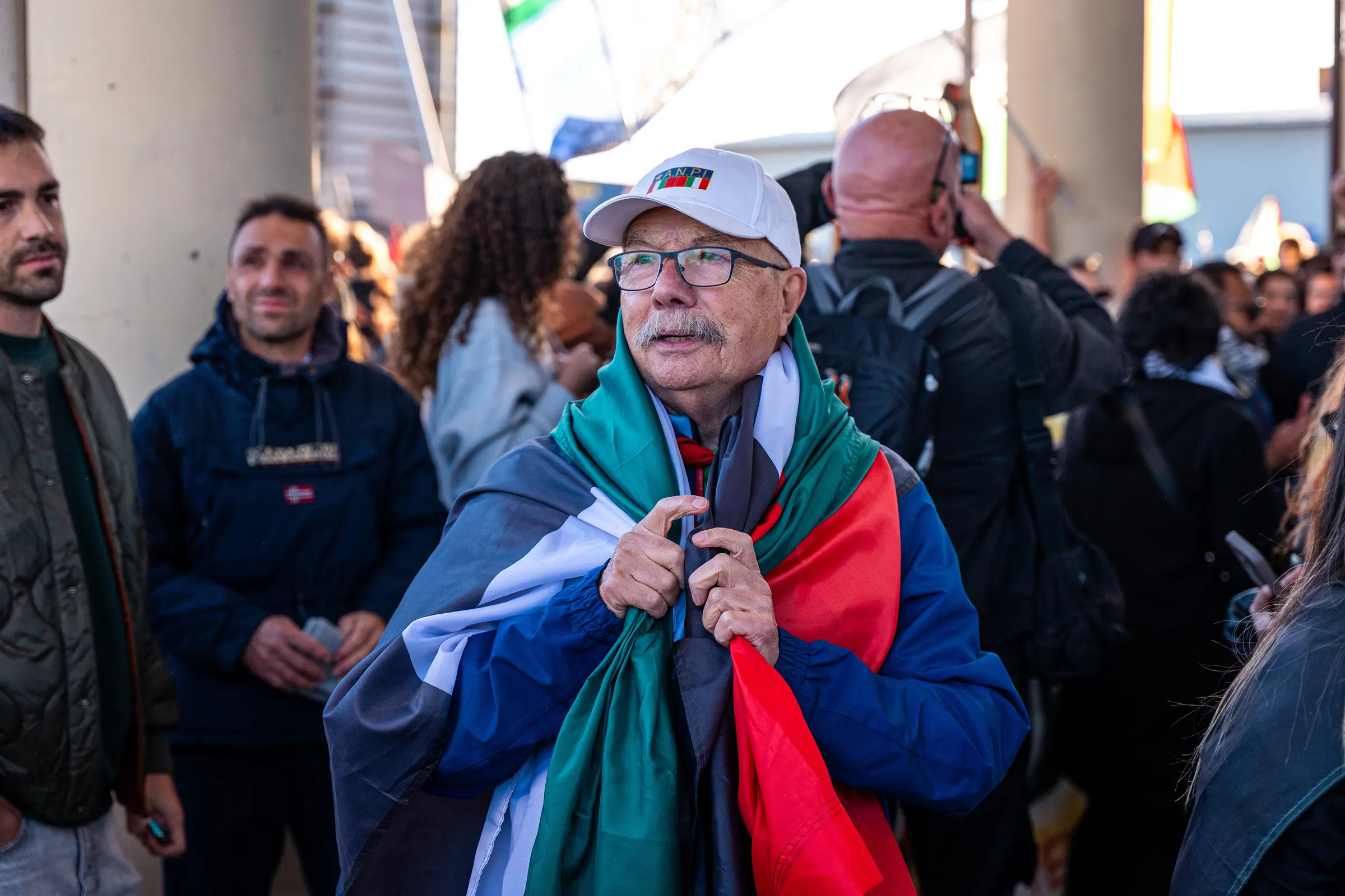 Uomo avvolto in una bandiera palestinese in mezzo al corteo
