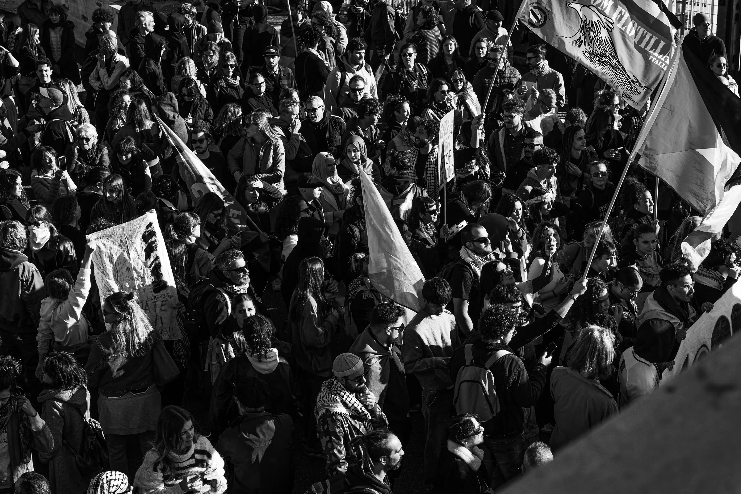 Folla di manifestanti con bandiere vista dall’alto, in bianco e nero