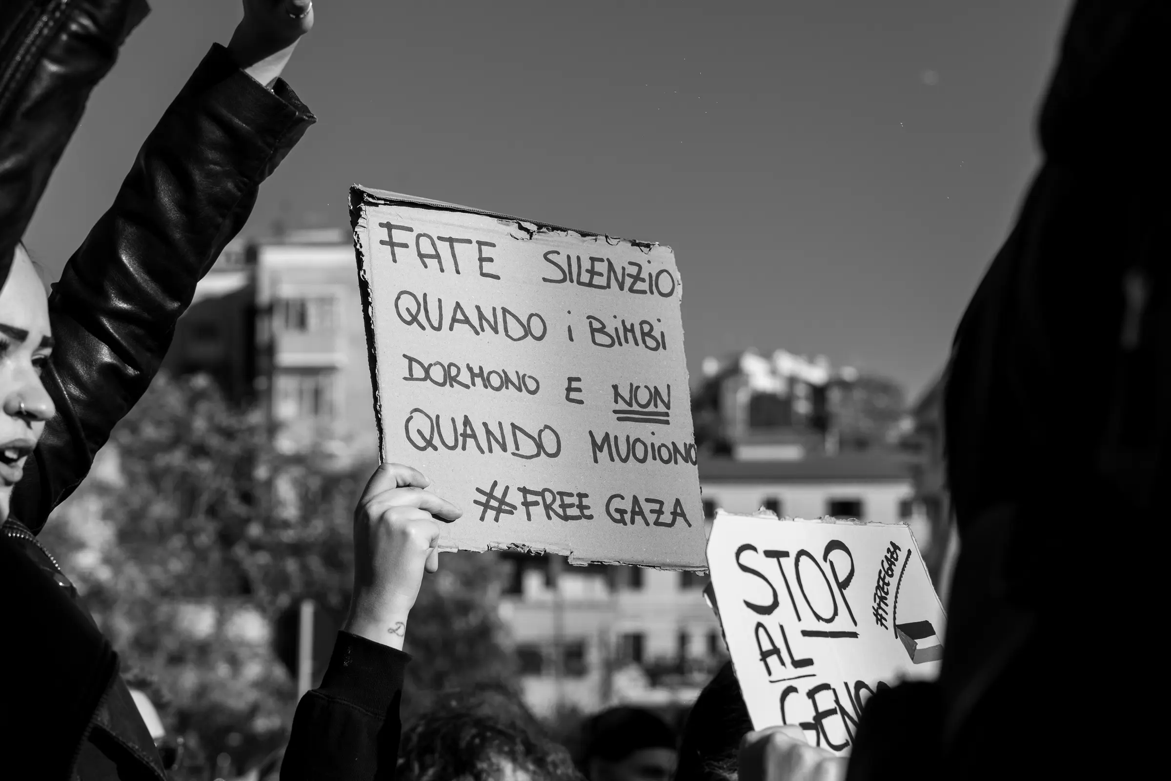 Cartelli scritti a mano alzati sopra la folla, in bianco e nero