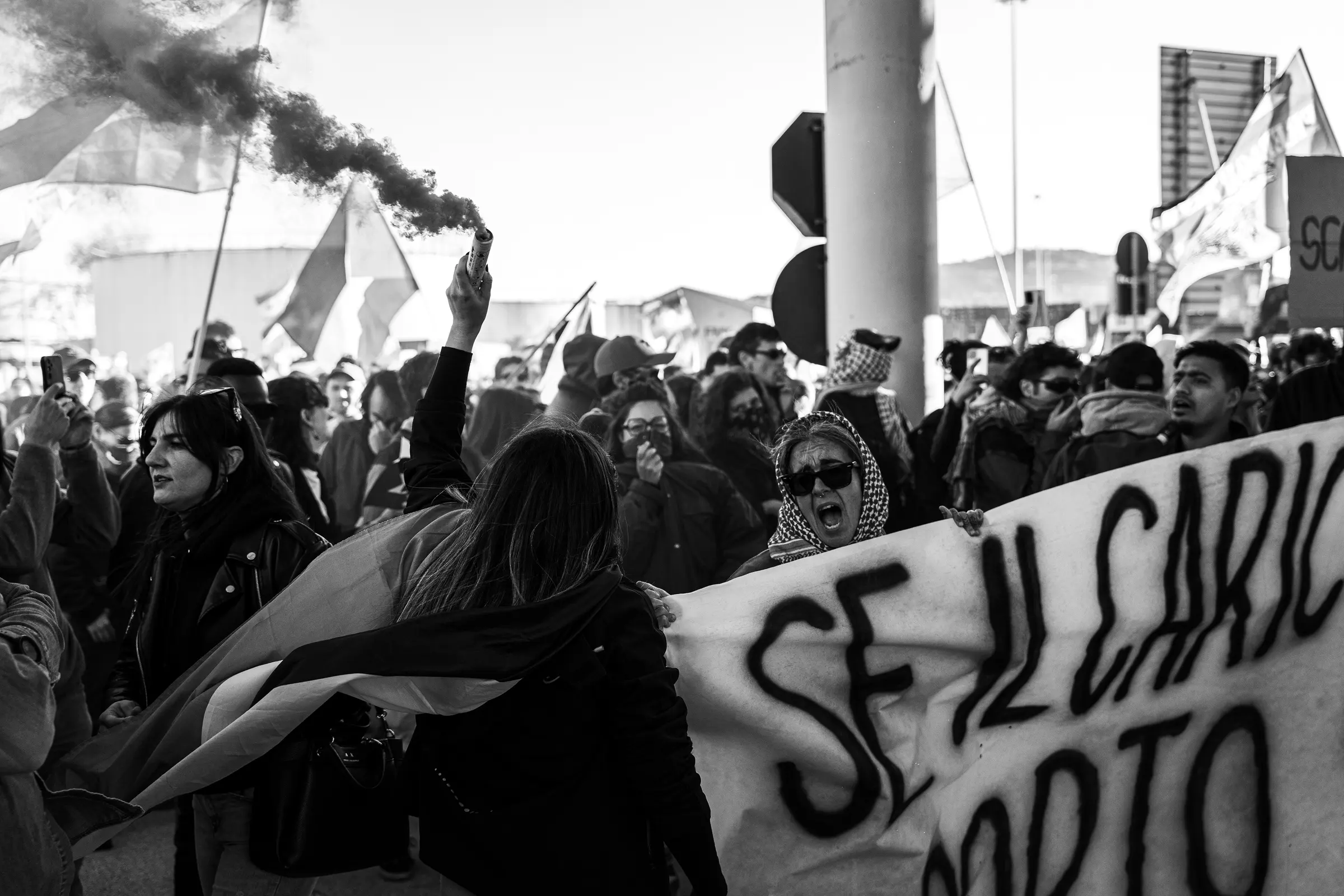 Corteo con striscione visto in controluce, in bianco e nero