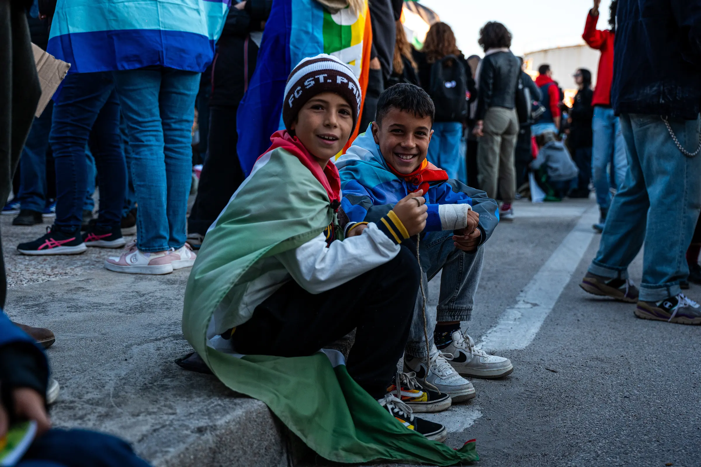 Due ragazzi seduti sul bordo della strada avvolti in una bandiera