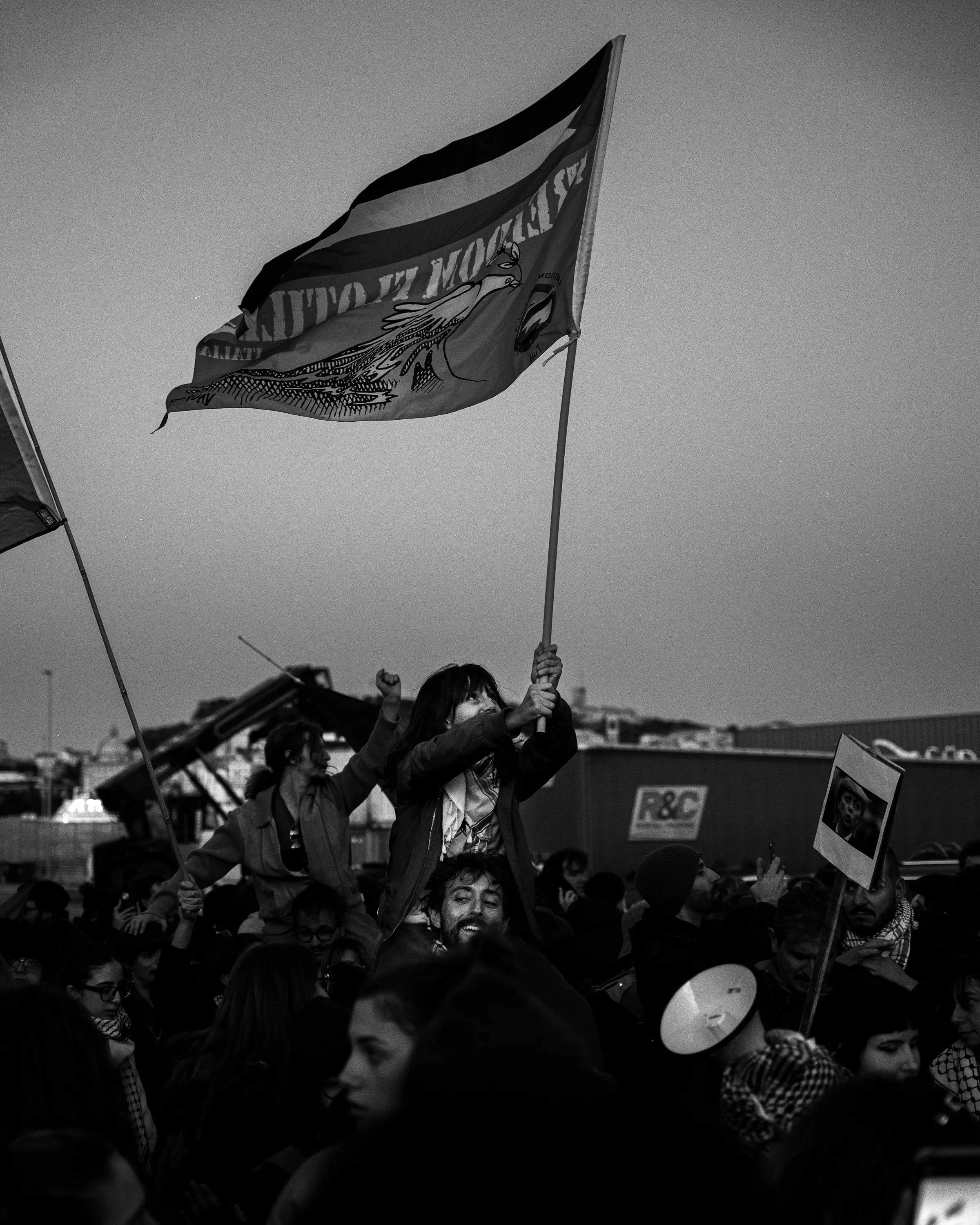 Bandiera che sventola sopra il corteo, in bianco e nero