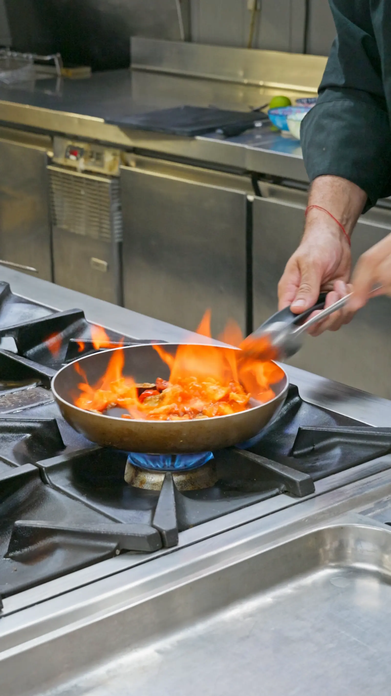 Padella che fiammeggia sul fuoco nella cucina del locale